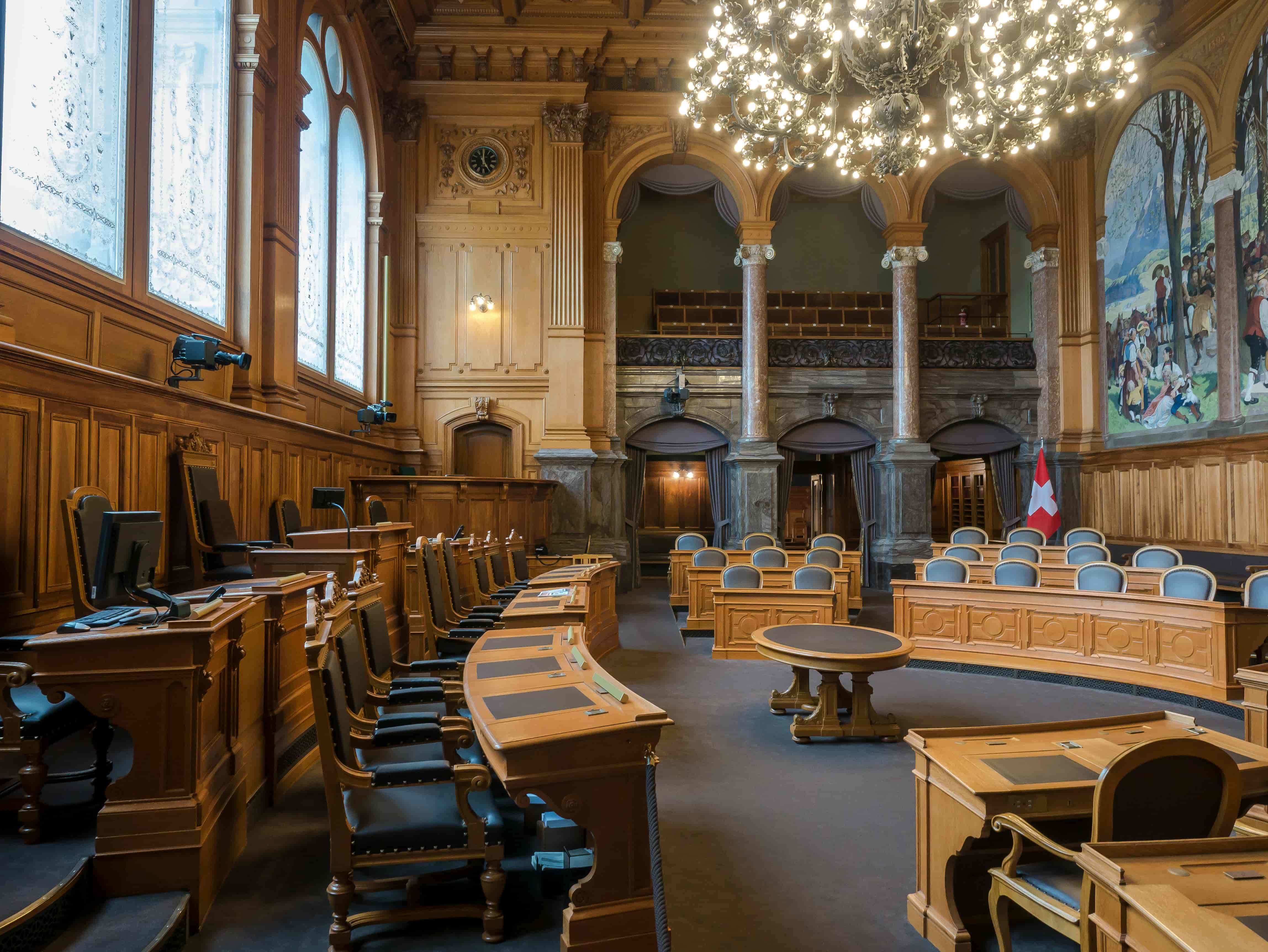 Formal chamber interior with wood paneling and chandelier, evoking authority and tradition